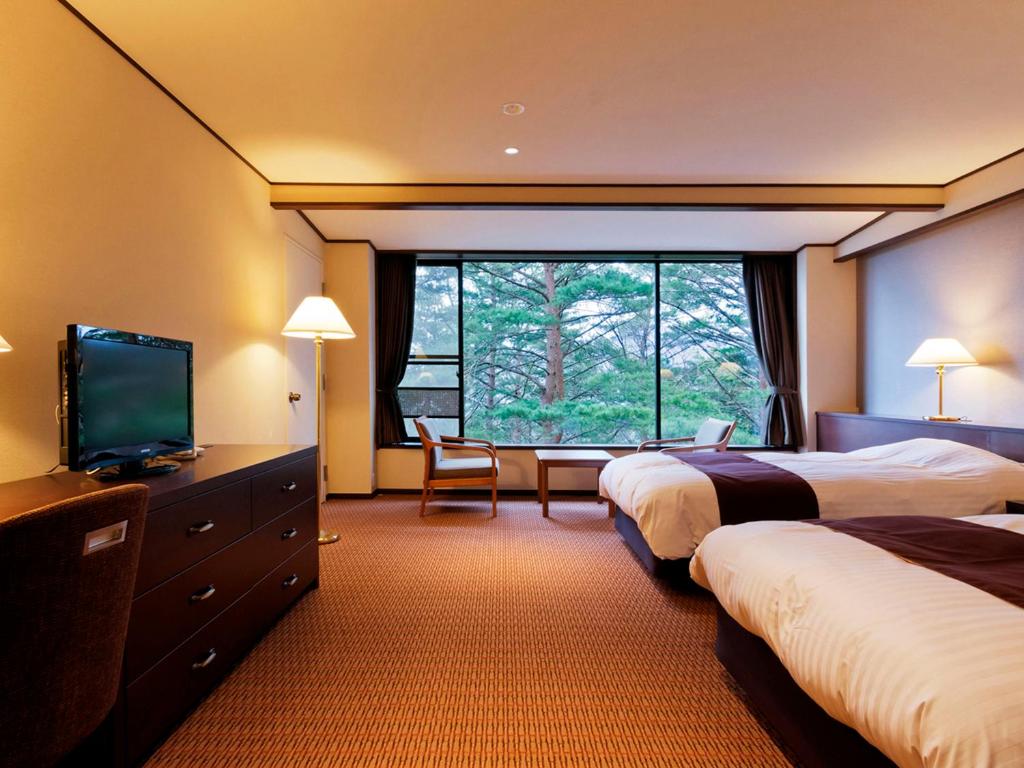 a hotel room with two beds and a flat screen tv at Jodogahama Park Hotel in Miyako