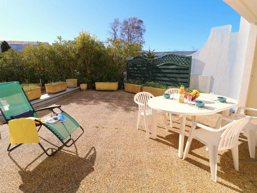 d'une terrasse avec une table et des chaises blanches. dans l'établissement Appartement 3P, Terrasse, 6 Pers, Piscine, Garage, Proche Plage et Commerces - FR-1-307-94, au Grau-du-Roi