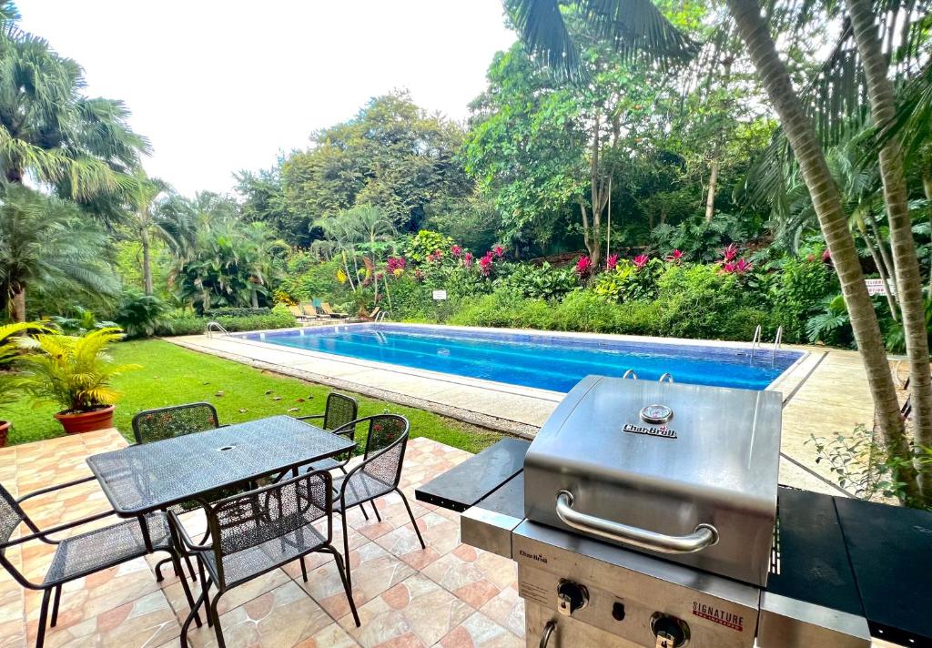 a grill and picnic table next to a swimming pool at The Oaks Tamarindo Primer piso, 22, 49, 73 in Tamarindo