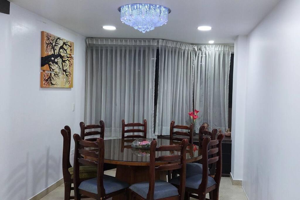 comedor con mesa, sillas y lámpara de araña en Hermoso y amplio apartamento, Embajada Americana, en Quito
