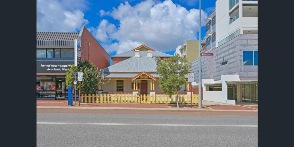 a building with a yellow fence on a city street at Emu Backpackers Perth - note - Valid passport required to check in in Perth