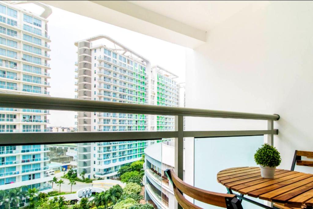 a balcony with a wooden table and views of buildings at AZURE Urban Resort Residences Condominium in Manila