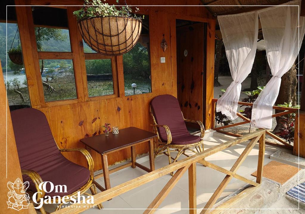 two chairs and a table in a room with windows at Om Ganesha in Palolem