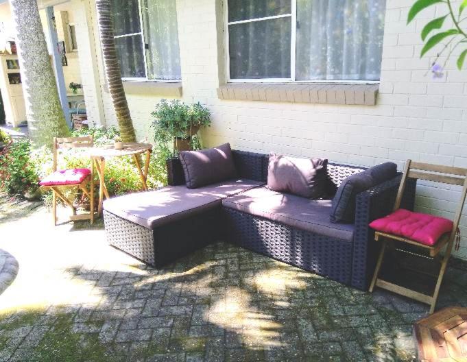um sofá de vime sentado fora de uma casa em Kincumber Guest Suite em Kincumber