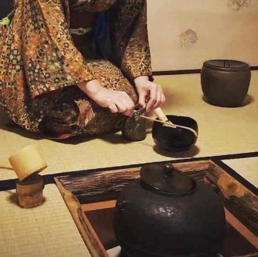 Eine Frau streckt eine Vase auf einen Tisch in der Unterkunft Ryokan Tori in Kyoto