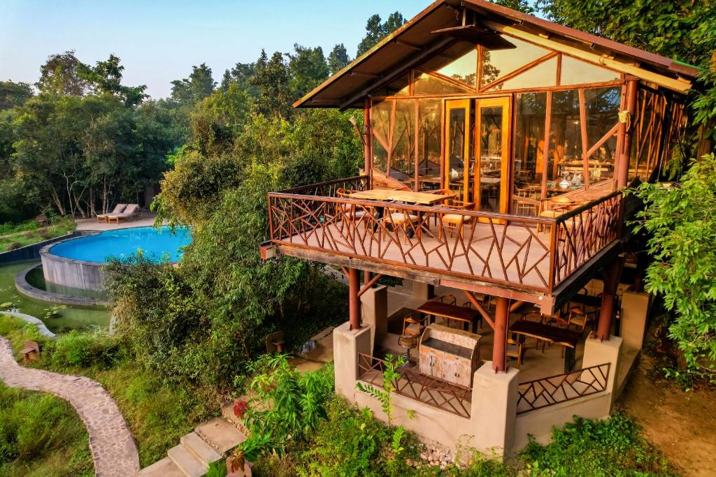 a house with a wrap around deck and a pool at Kanha Jungle Camp in Kānha