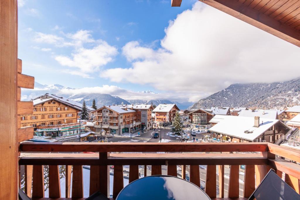 a view from a balcony of a town with snow covered mountains at No 8 Bed & Bar in Verbier
