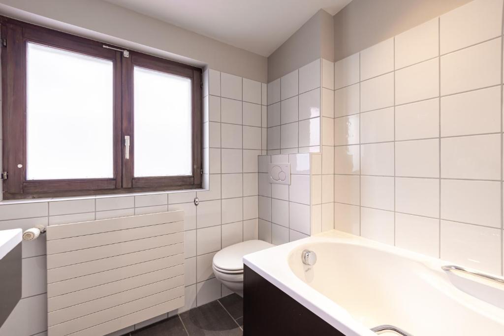 a white bathroom with a tub and a toilet at No 8 Bed & Bar in Verbier