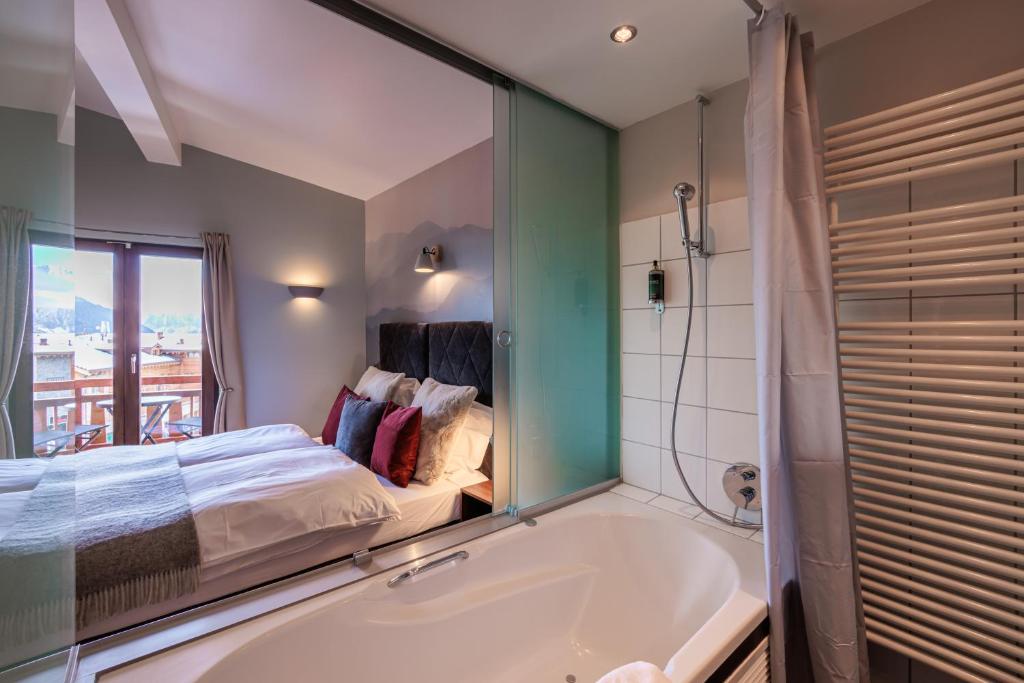 a bathroom with a tub and a bed and a window at No 8 Bed & Bar in Verbier
