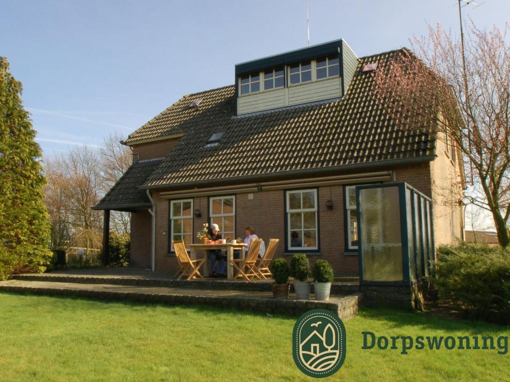 a couple sitting at a table in front of a house at Authentic Holiday Home in North Brabant by the Forest in Leende