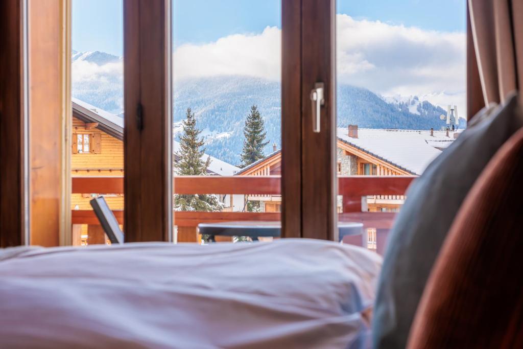 a bed looking out a window at a mountain view at No 8 Bed & Bar in Verbier