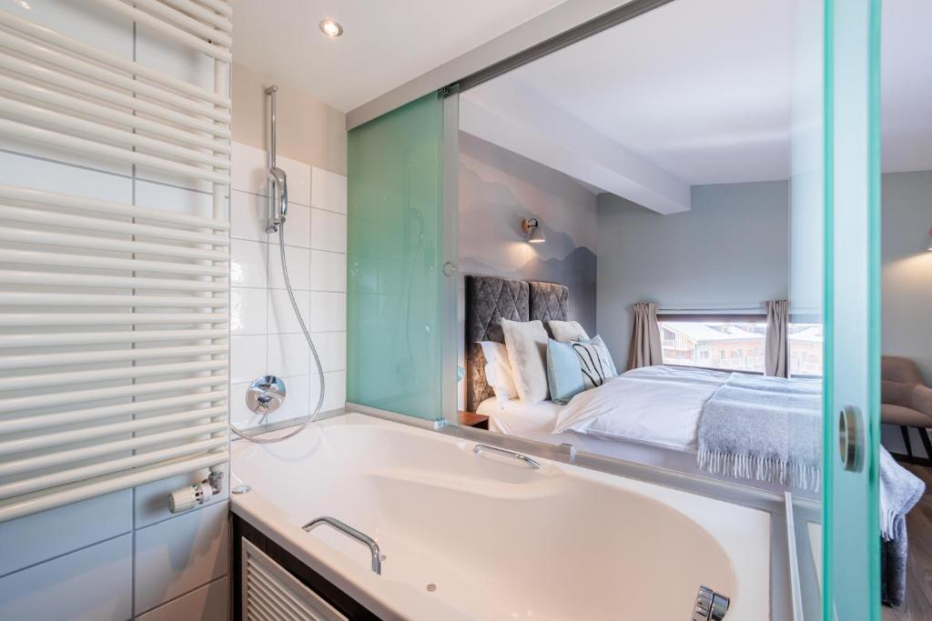 a bathroom with a tub and a bed and a mirror at No 8 Bed & Bar in Verbier