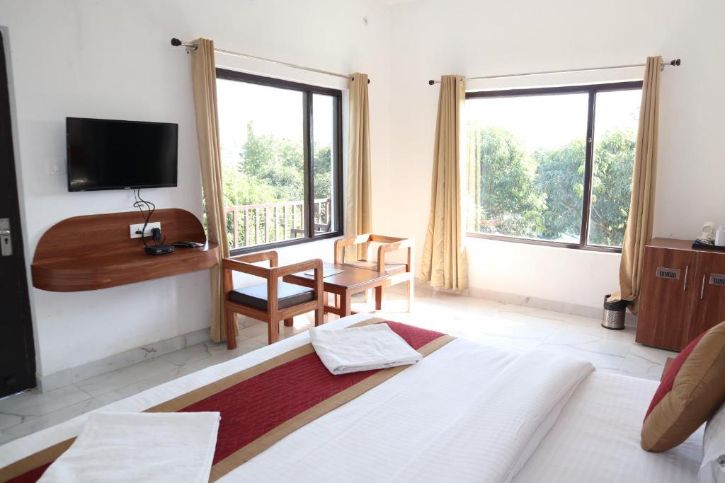 a bedroom with a bed and a desk and a tv at Seven Corbett in Rāmnagar