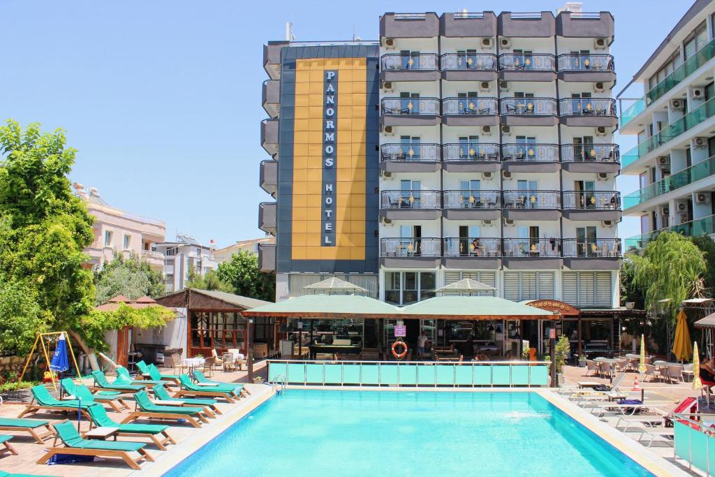 un hôtel avec une piscine et des chaises longues et un hôtel dans l'établissement Panormos Hotel, à Didim