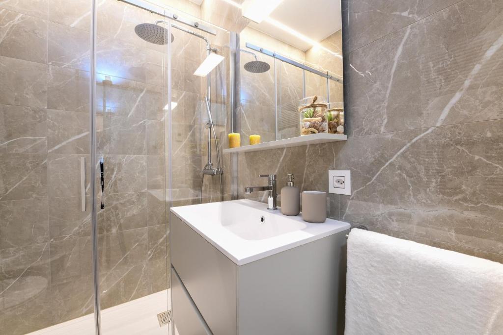a bathroom with a white sink and a shower at Lake Modern Suites - Free Parking in Lugano