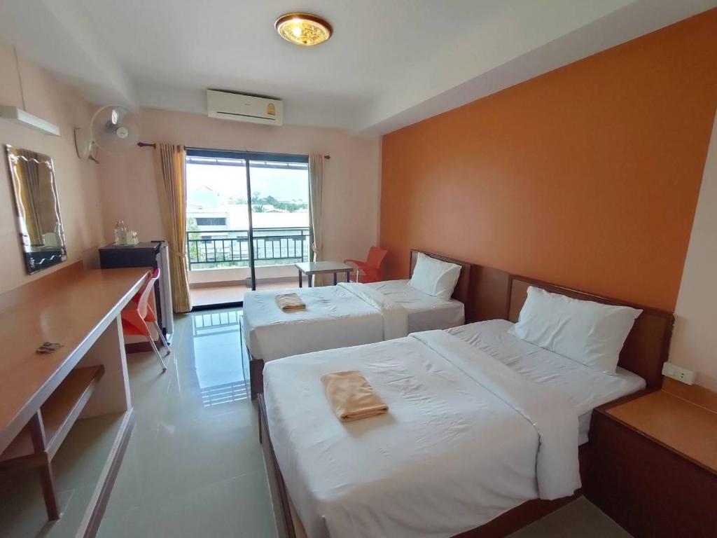 een hotelkamer met 2 bedden en een bureau bij ธรดา in Ban Pa Kluai