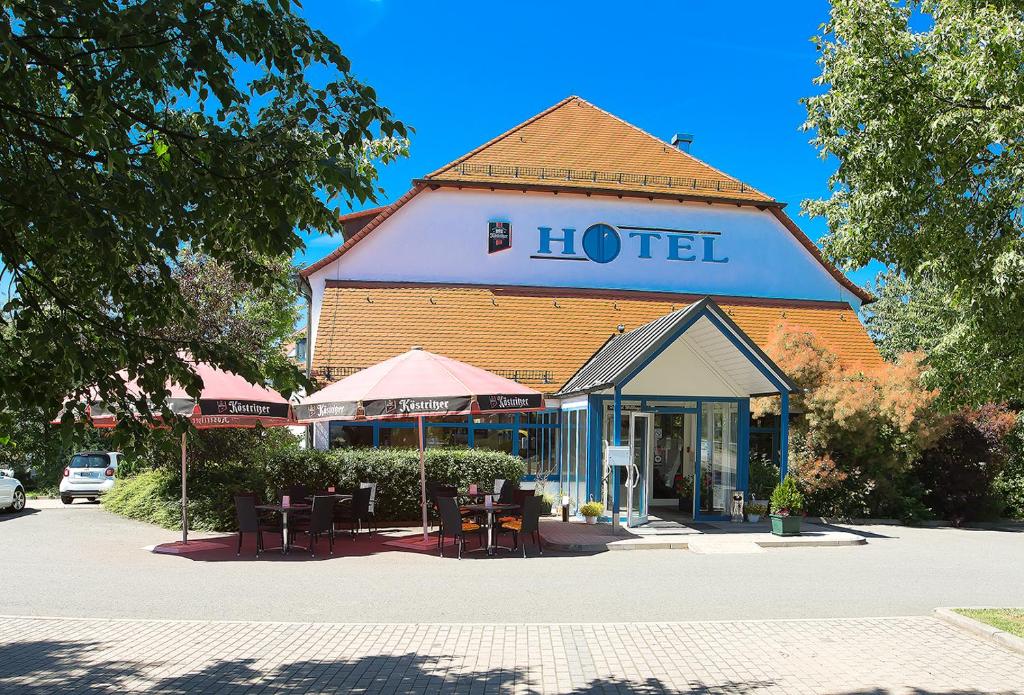 ein Hotelgebäude mit Tischen und Stühlen davor in der Unterkunft Apart Hotel Gera in Gera