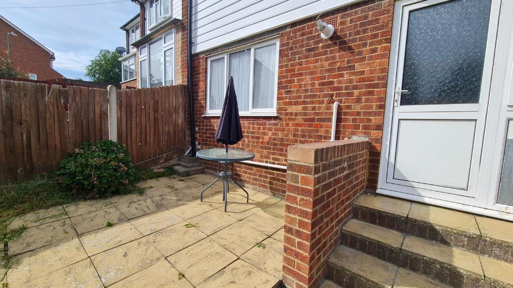 une terrasse avec une chaise et un parasol à côté d'une maison dans l'établissement Dartford Kent House - Hosted by Castile Accommodations Ltd, à Kent