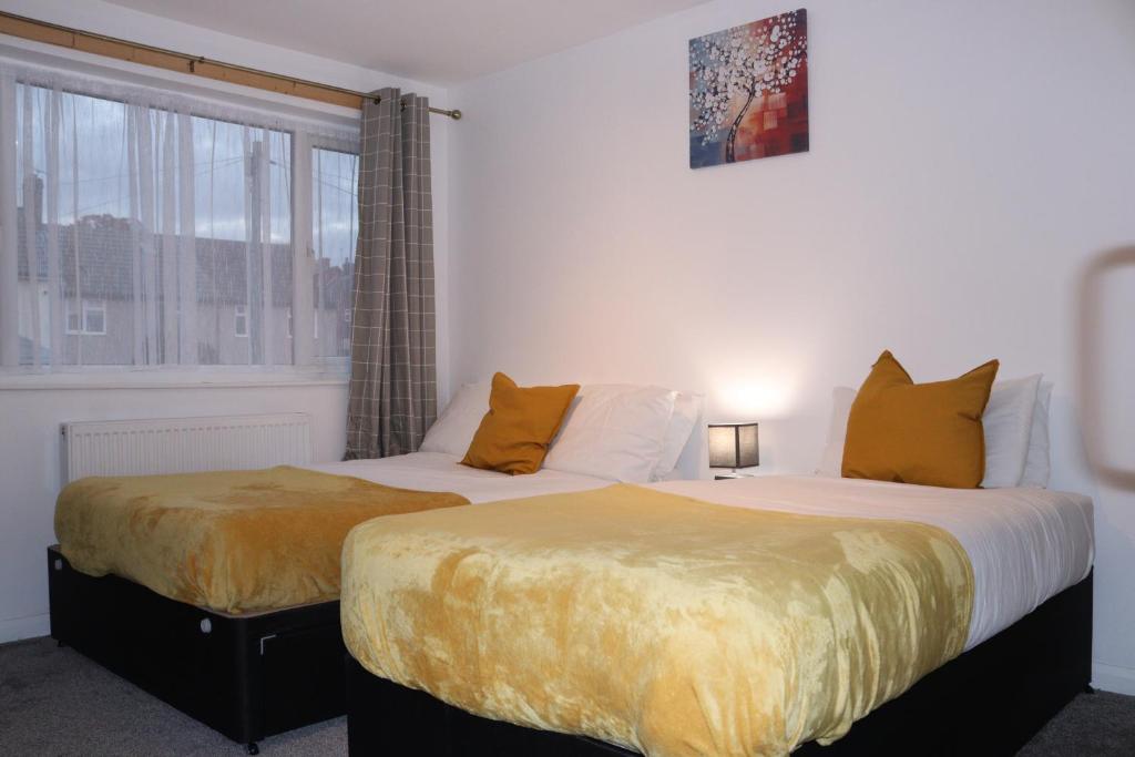 two beds in a room with a window at Dartford Kent House - Hosted by Castile Accommodations Ltd in Kent