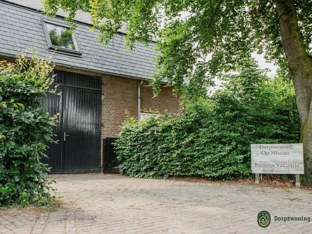 un edificio de ladrillo con una puerta negra y una señal en Vibrant Farmhouse near Forest in Heeze-Leende, en Leende