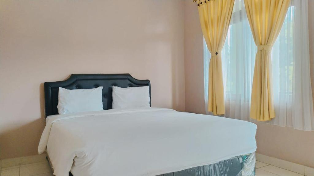 a bedroom with a bed and a window with yellow curtains at PURNAMA HOUSE KUTA in Kuta