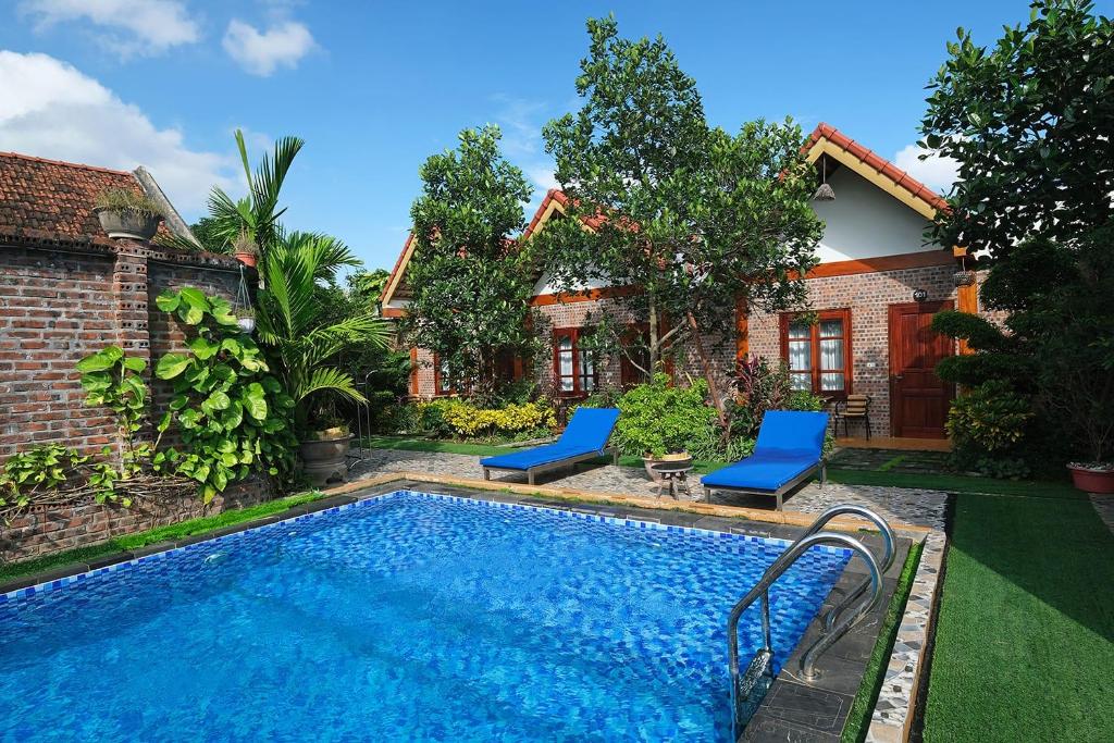 - une piscine avec 2 chaises bleues à côté d'une maison dans l'établissement Tamcoc Mr. Cau Homestay, à Ninh Binh