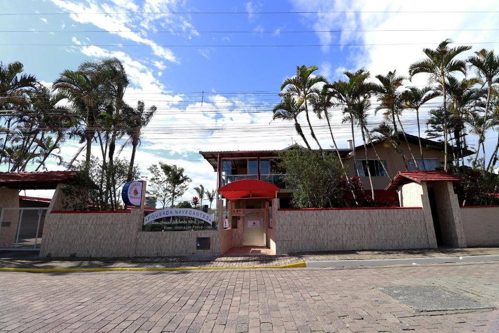 a house with palm trees in front of a building at Pousada Navegantes in Navegantes