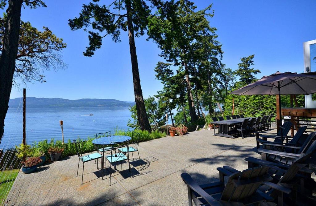 a patio with tables and chairs and a view of the water at Pendray House in North Saanich