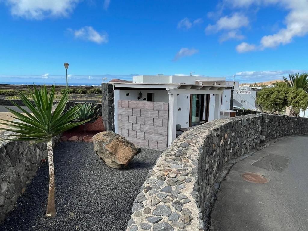 a building with a stone wall and a palm tree at Sun, Relax & Lava, Free wifi 600mb, BBQ in Tinajo