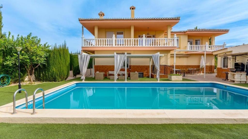 una villa con piscina di fronte a una casa di Villa de la Acacia a Gójar