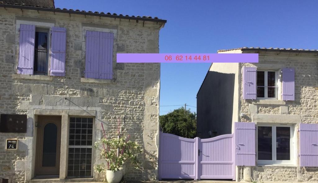 uma casa velha com portas roxas e uma cerca em Accacia Home em Ferrières