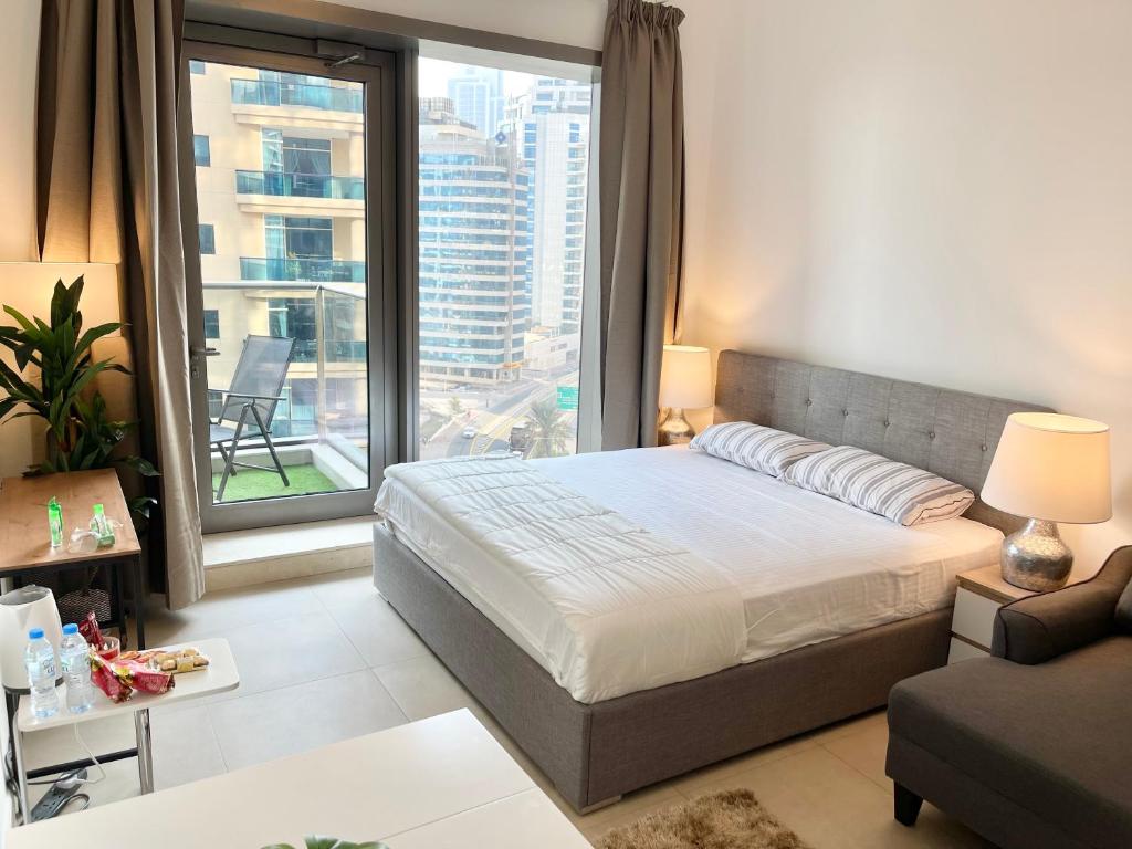 ein Schlafzimmer mit einem Bett und einem großen Fenster in der Unterkunft Super Elegant studio apartment-Sparkle tower By SWEET HOMES in Dubai