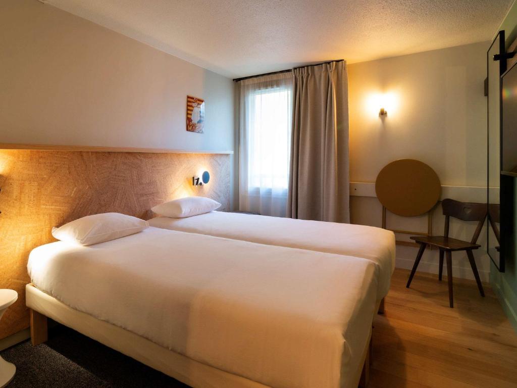 ein Hotelzimmer mit einem großen weißen Bett und einem Fenster in der Unterkunft Greet Hotel Colmar in Colmar