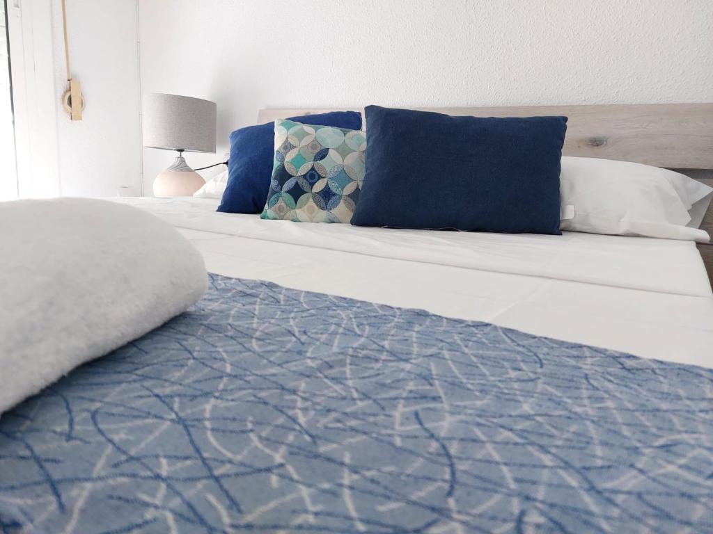 a bed with blue and white pillows on it at SDH apartments in Alicante