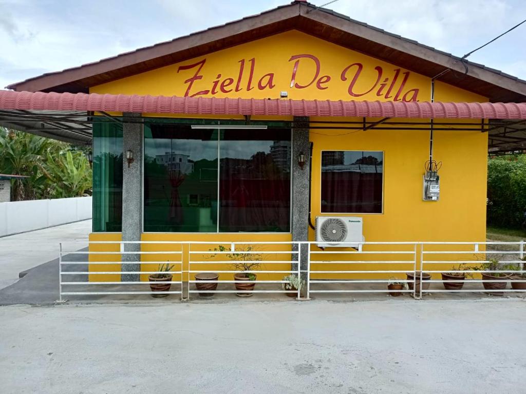 um edifício amarelo com um sinal que diz olá bella em Ziella De Villa em Pantai Cenang