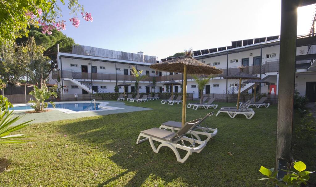 un patio con tumbonas, una sombrilla y una piscina en Campomar Playa, en El Puerto de Santa María