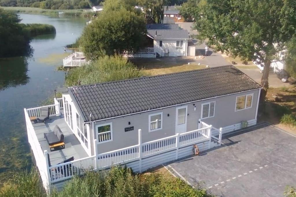 an aerial view of a white house next to a river at Chichester Lakeside Holiday Park Lakefront Lodge in Merston