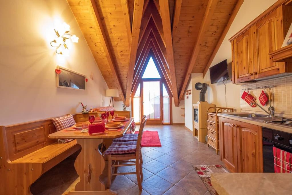 a kitchen with a wooden table and a wooden ceiling at Happy Guest Apartments - Alpin Chalet Borno in Borno