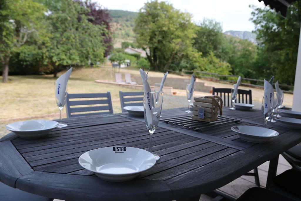 a wooden table with bowls and wine glasses on it at Private riverside villa with breathtaking views in Axat