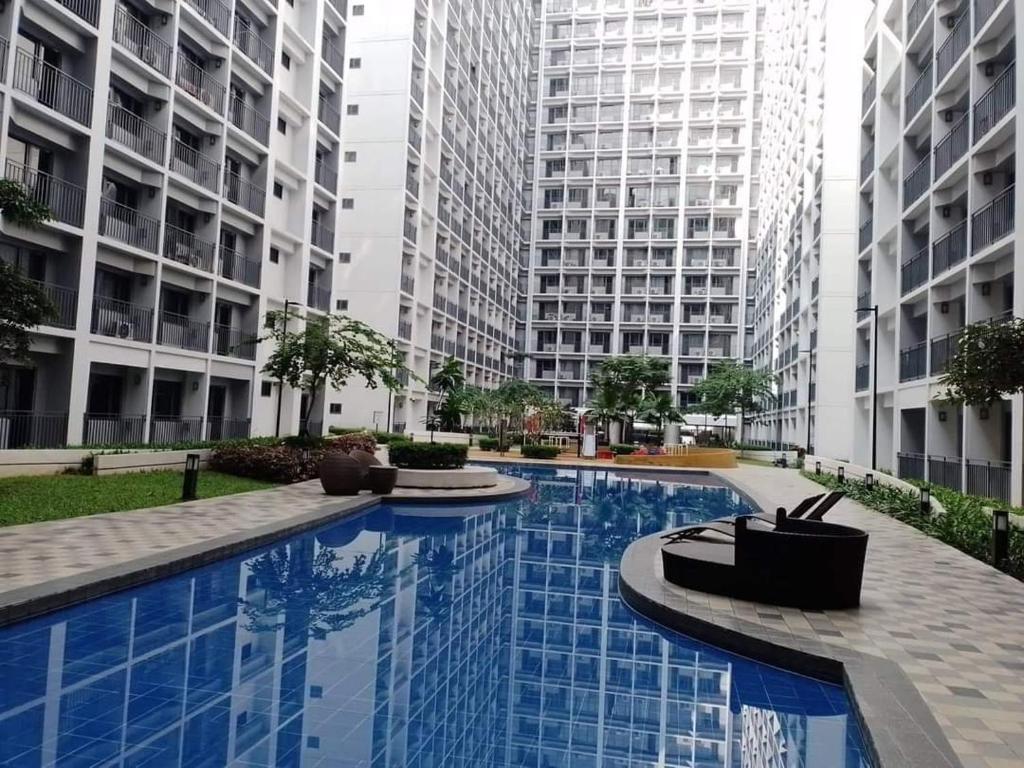 a large swimming pool in the middle of two tall buildings at Your home in the city in Manila