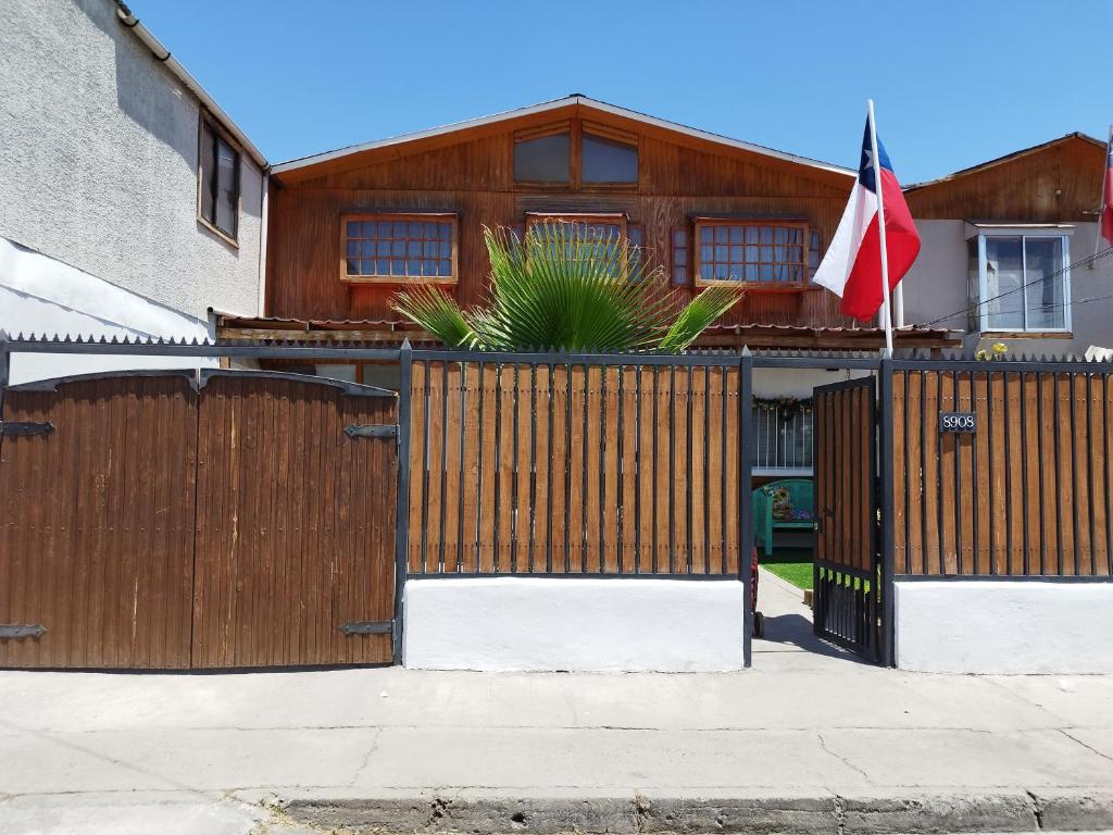 a house with a wooden fence and a flag at Hostal Sol y Luna in Santiago