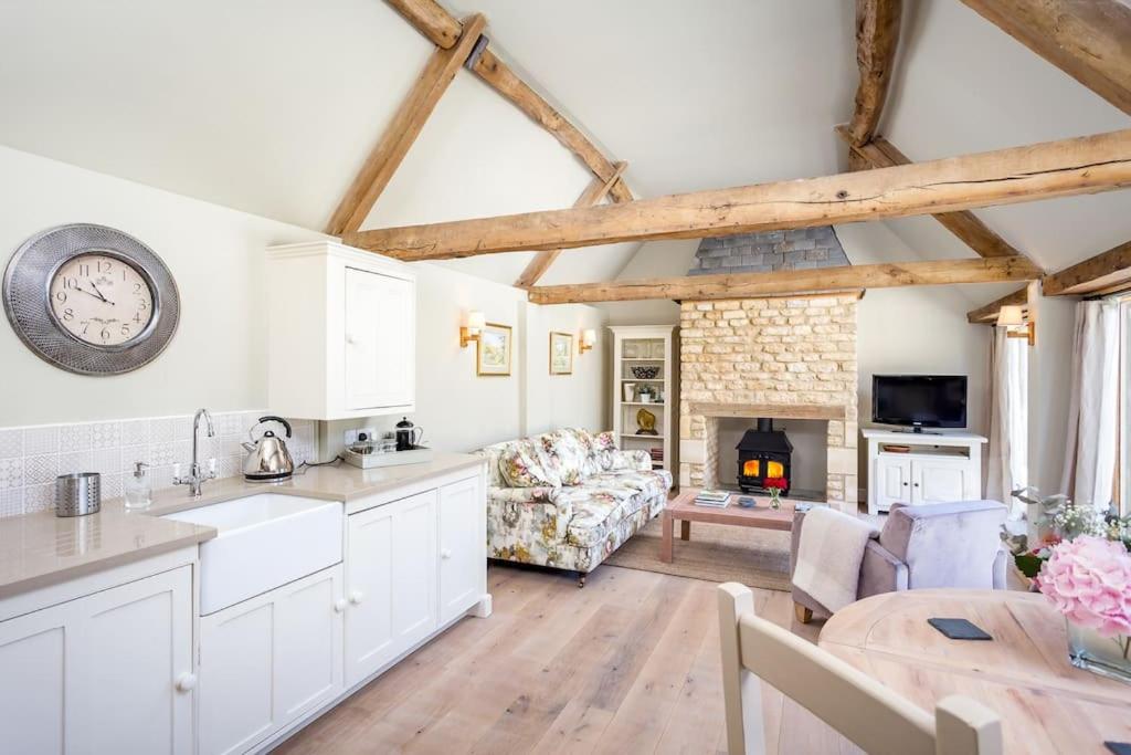 a kitchen and living room with a clock on the wall at Clematis cottage in Cheltenham