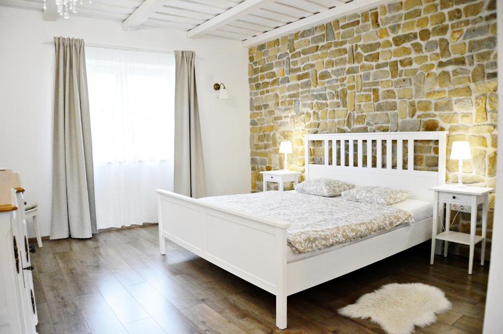 a bedroom with a white bed and a stone wall at R Cottage Jacuzzival in Balatonfenyves