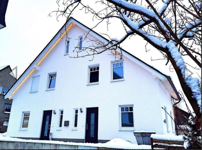 ein großes weißes Haus mit Schnee auf dem Boden in der Unterkunft Apartment-Sauerland in Schmallenberg