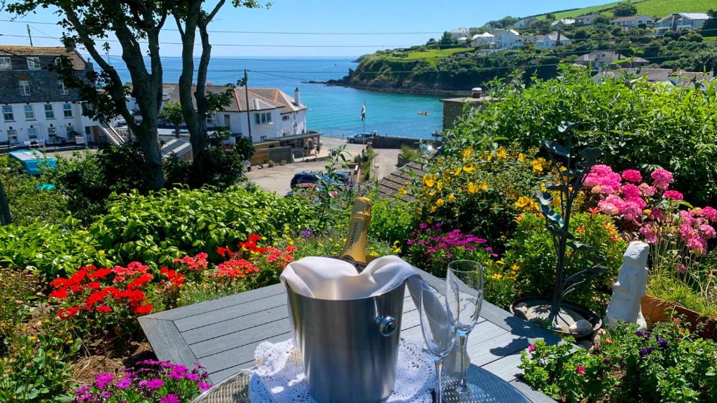 Portmellon Cove Guest House في ميفاغيسي: طاولة مع زجاجة من النبيذ والزهور عليها