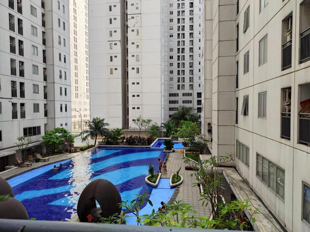 an overhead view of a swimming pool in a city with tall buildings at Apartemen Bassura City by Globy Property in Jakarta