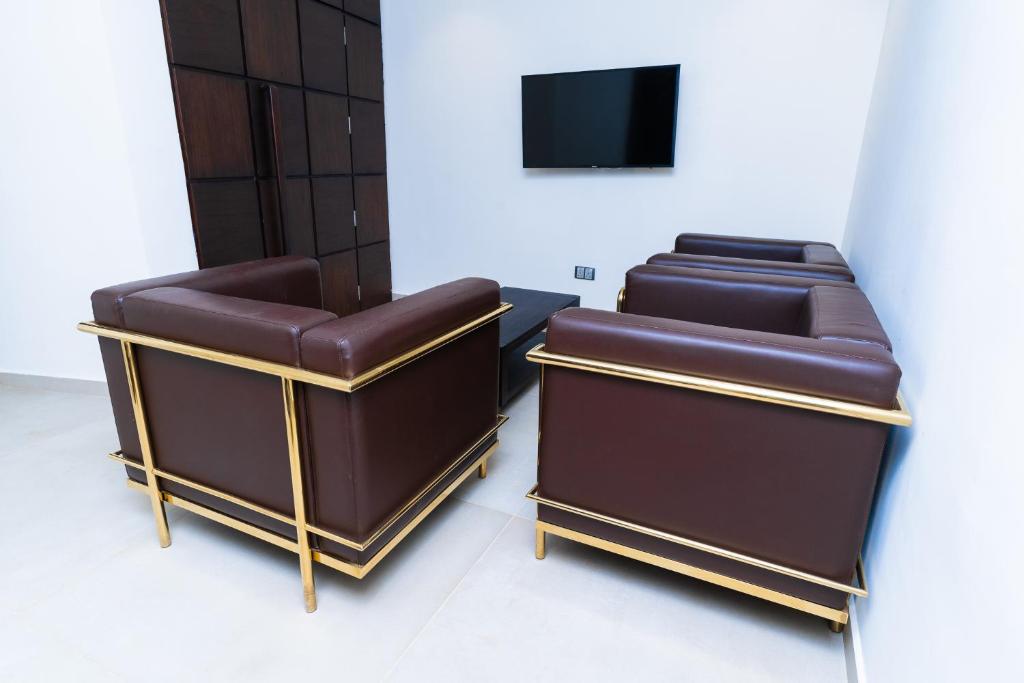 two brown leather chairs in a room with a tv at Terraform Hotel in Lagos