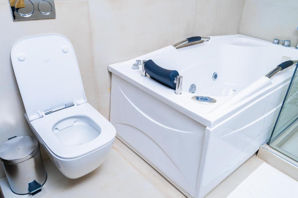 a white bathroom with a toilet and a sink at Terraform Hotel in Lagos