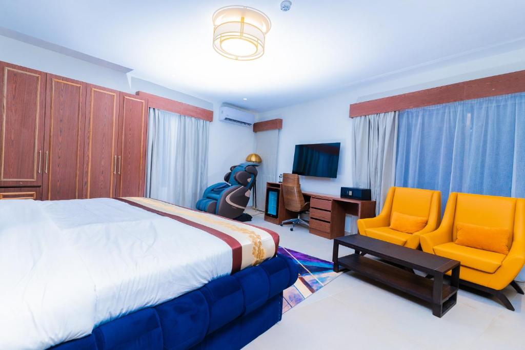 a bedroom with a bed and two yellow chairs at Terraform Hotel in Lagos