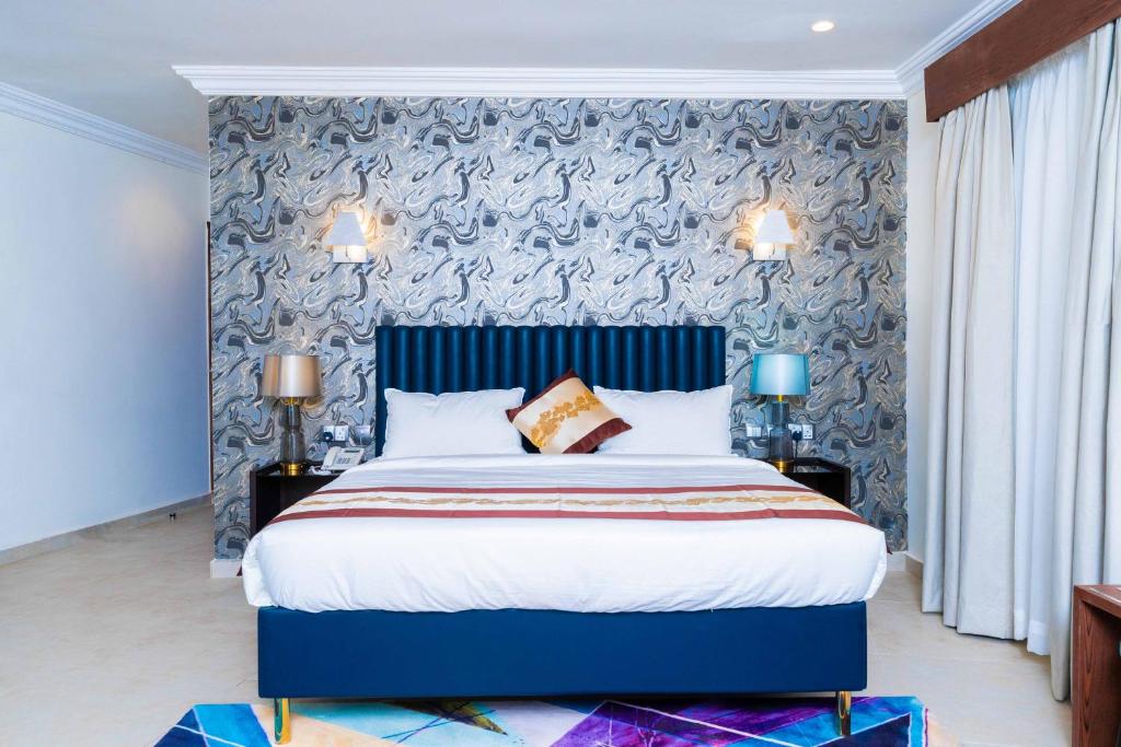 a bedroom with a large bed with a blue headboard at Terraform Hotel in Lagos